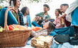 Group of smiling friends making barbecue in the nature - Happy people having fun on a pic-nic in the countryside - Lifestyle concept about boys and girls are all happy and playing guitar