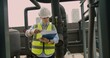 © HarryKiiM Stock - Engineer in hard hat and reflective vest inspecting paperwork at an urban industrial site examining a document on a rooftop with industrial pipes and valves in the background