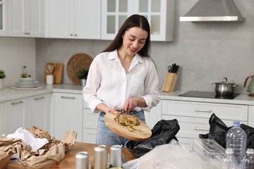 Sticker - Garbage sorting. Woman putting food waste into plastic bag at table in kitchen