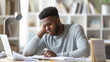 © MP Studio - A stressed person at a desk holds their head in dismay while looking at a laptop screen, with eyeglasses set aside.