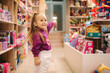 © Aleksandr - Adorable little girl shopping for toys. Cute female in toy store. Happy young girl selecting toy