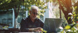 © Ai Studio - Mature man working remotely on laptop in an outdoor cafe, enjoying urban life