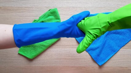 Wall Mural - Two hands in rubber gloves wipe table with cleaning rags. 2 cleaners clean wooden surface close-up. Teamwork. Space for text, design, advertising, at end of video on background of empty tabletop.