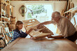 © Marko Geber - Grandfather and grandson building a wooden model in a workshop
