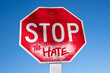 © david - Red stop sign with blue sky reading stop the hate in spray paint