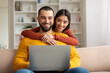 © Prostock-studio - Happy young couple websurfing on laptop together while relaxing at home