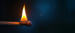 A close-up of a burning wooden match on black background. Match head with burning gray at the end, flames, copy space. Creative banner of energy, fuel industry.