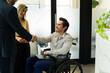 © AntonioDiaz - Happy businessman in a wheelchair meeting some new clients in an office