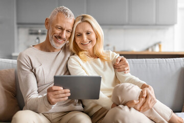 Wall Mural - Happy Senior Couple Using Digital Tablet Together Browsing Internet