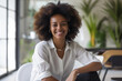 Smiling woman sitting position on a chair in minimalist interior background, Confident African woman with curly afro hair, Employee of the Month wallpaper concept, beautiful elegant woman portrait