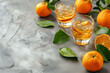 Alcoholic cocktail with mandarins. shot of fresh tasty citrus juice in glass and ripe tangerines. Cold summer drink with citrus slices, ice and rosemary on grey rustic background. Close up. Selective 