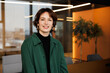 © Girts - Confident young professional woman working in a modern office. Business trip woman posing for camera for business portraits in green shirt. A young marketing specialist inspired to work