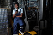 © pressmaster - Young male engineer of industrial plant sitting by door of forklift and texting in mobile phone while having break after work
