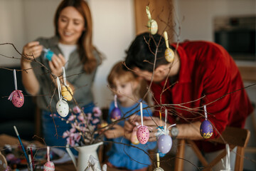 Parents and daughter joyfully preparing for Easter with colorful decorations