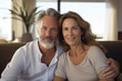 © Olivia - Beautiful middle aged spain woman and man sitting on sofa at home, mature senior in living room