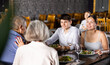 © JackF - Elderly couple and young couple chatting and enjoying dinner in restaurant