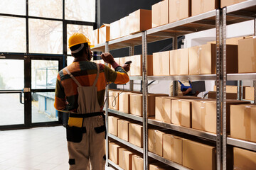 Wall Mural - African american delivery service managers scanning parcel barcode before dispatching. All black shipping company workers team using scanner on cardboard boxes in storehouse