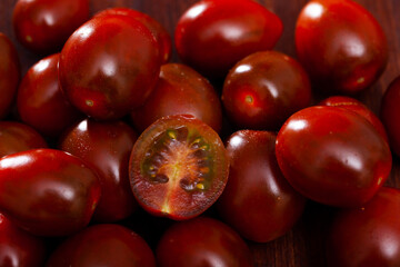 Wall Mural - Ripe red cultivated species kumato tomatoes on wooden background. Healthy vitamin product