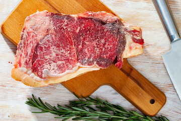 Raw beef entrecote on wooden board with rosemary