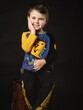 Cute little 5 year old laughing boy sitting on brown leather suitcase in studio