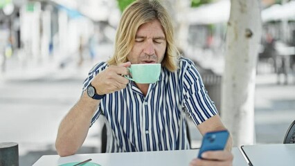 Sticker - Middle-aged man drinking coffee browsing smartphone at an outdoor cafe