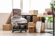 © Pixel-Shot - Interior of light office with chair wrapped in stretch film and cardboard boxes on moving day