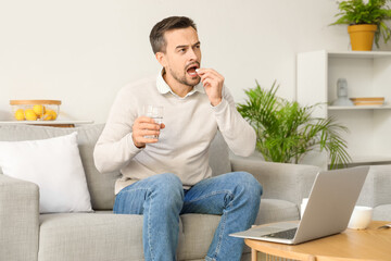 Canvas Print - Ill young man taking pill while video chatting with doctor on laptop at home