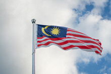 Malaysia Flag On A Pole Waving Against The Sky.