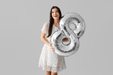 Poster - Happy young woman with silver air balloon in shape of figure 8 on grey background. International Women's Day