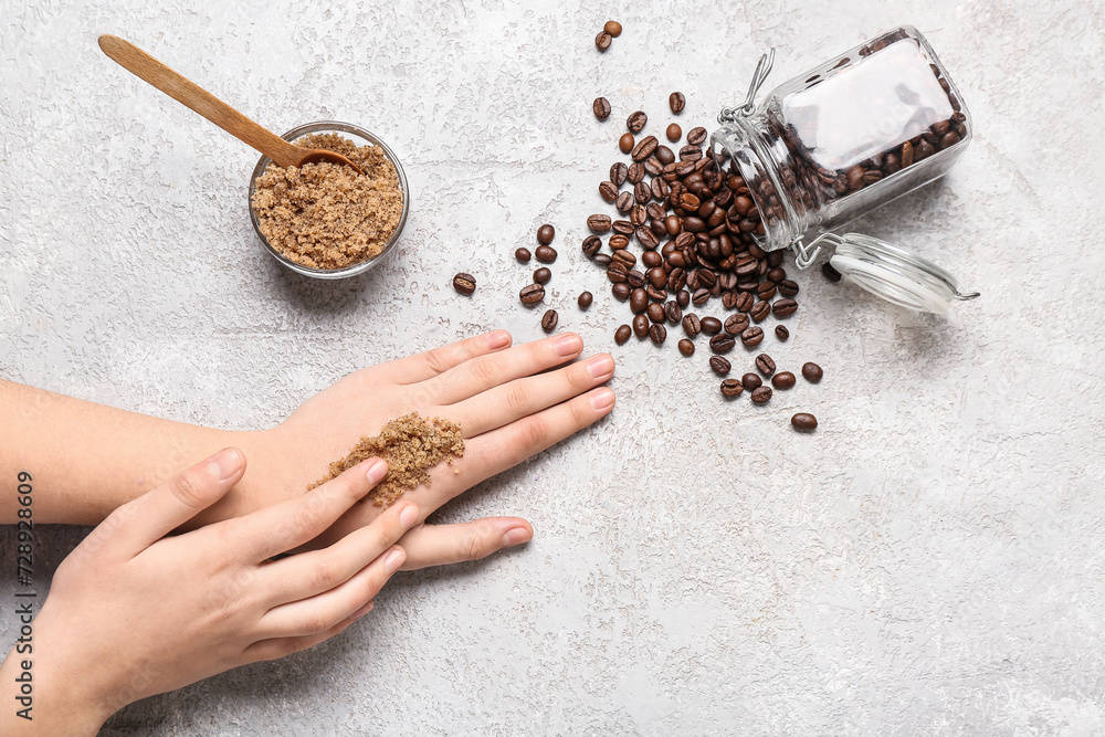 Woman applying coffee scrub onto her hands on light background, closeup