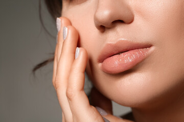 Poster - Young woman with beautiful lips and stylish manicure on grey background, closeup