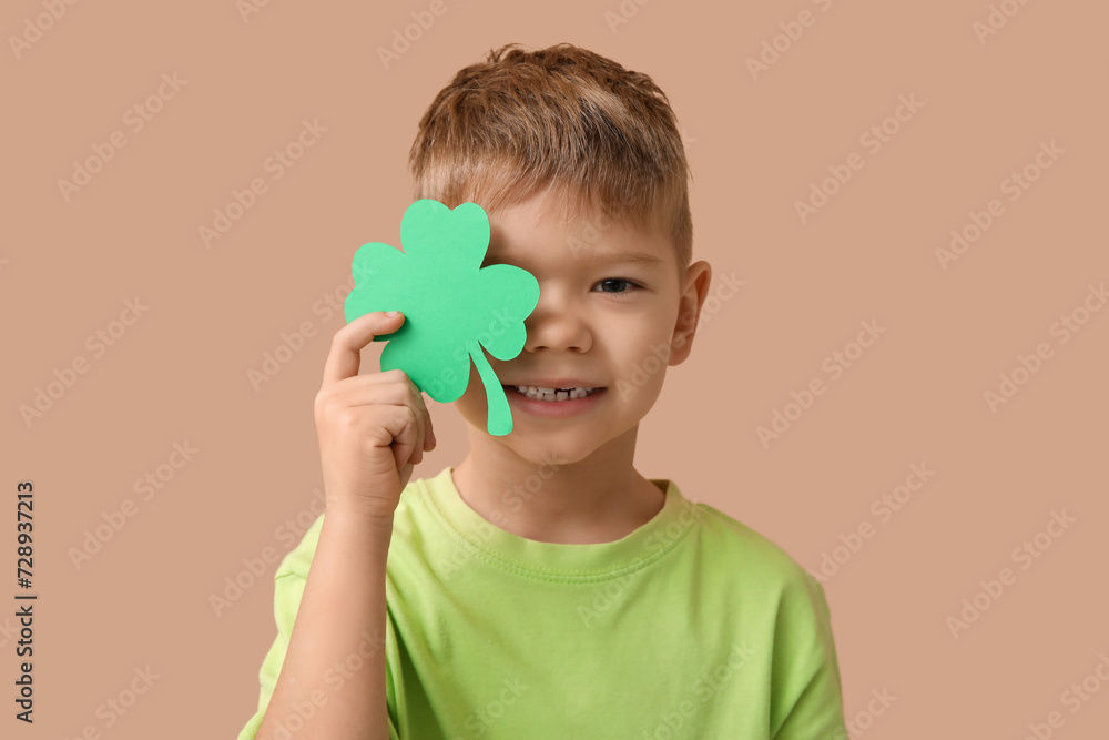 Cute little boy with clover on brown background. St. Patrick's Day celebration