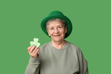 Wall Mural - Senior woman in leprechaun hat with clover on green background. St. Patrick's Day celebration