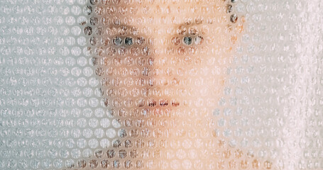 Plastic pollution. Contamination problem. Environmental disaster. Textured art portrait of anxious scared woman face silhouette behind bubble wrap on white background.