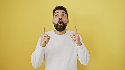 Poster - Joyful young man stands amazed, pointing, looking up with surprise on isolated yellow background, his smile oozing positivity, confident in his lottery win