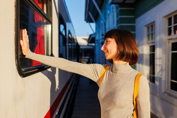 young traveler with a backpack stands on the platform and says goodbye, saying goodbye before leaving.