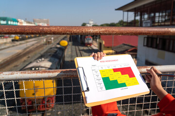 Wall Mural - action of a business manager is holding project risk assessment form on blurred background of train 
