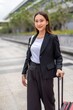 © StockPhotoRepublic - Asian businesswoman with luggage looking at camera, going on business trip