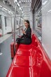 © StockPhotoRepublic - Asian businesswoman with luggage using phone while taking a public skytrain transport to the airport
