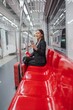 © StockPhotoRepublic - Asian businesswoman with luggage using phone while taking a public skytrain transport to the airport