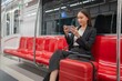 © StockPhotoRepublic - Young Asian Businesswoman Using Phone On The Public Skytrain