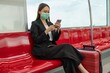 © StockPhotoRepublic - Asian businesswoman wearing mask while traveling in a public skytrain on the way to the airport