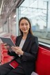 © StockPhotoRepublic - Asian businesswoman using digital tablet in a public skytrain while traveling to the airport for a business trip