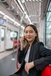 © StockPhotoRepublic - Asian businesswoman talking on phone while on the way traveling to the airport in a metro skytrain