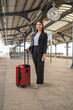 © asean studio - Young asian business woman holding phone and passport at a train station, waiting to departure to the city center