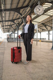 Fototapeta  - Young asian business woman holding phone and passport at a train station, waiting to departure to the city center