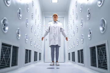 Wall Mural - Factory worker standing in industrial air blowing tunnel removing dust and particles before entering production line.