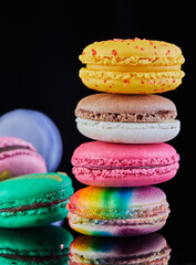 Wall Mural - Assorted colorful macarons folded and arranged on a black surface with reflection