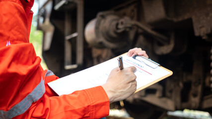 Wall Mural - action of a mechanic engineer is checking on heavy machine checklist form to verify the quality of m