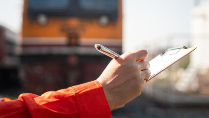 Wall Mural - a service technician is checking on heavy machine maintenance checklist, with an ancient train locom